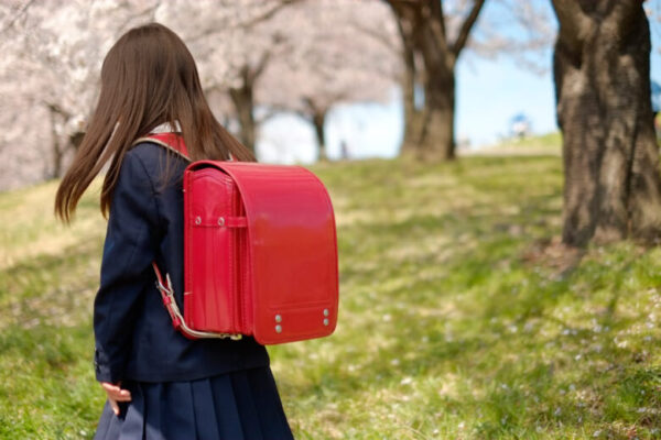 桜の木の下でランドセルを背負う少女